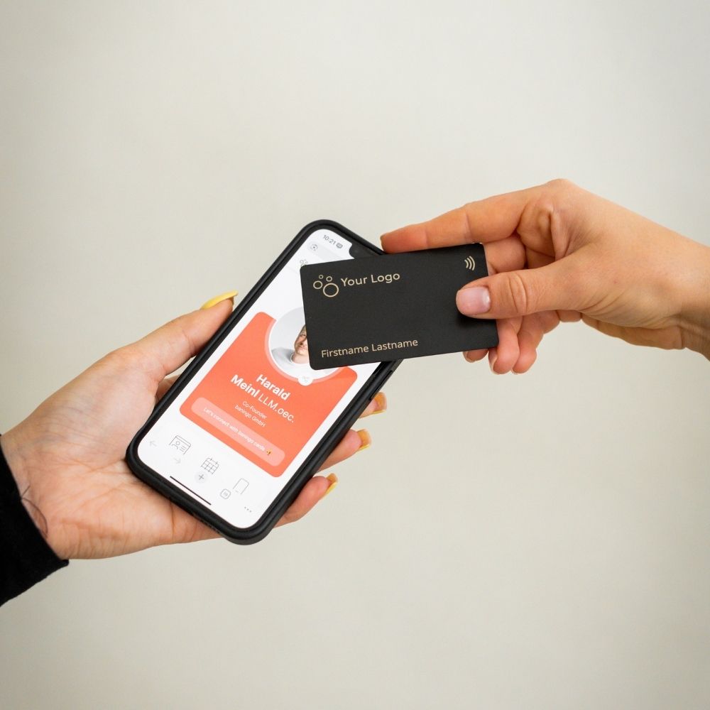 NFC Visitenkarte Metall wird von einem Smartphone getappt, das eine geöffnete digitale Visitenkarte anzeigt