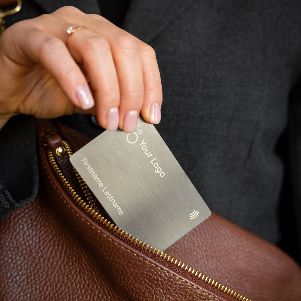 Brushed Metal Grey NFC Business Card being pulled out of a brown handbag
