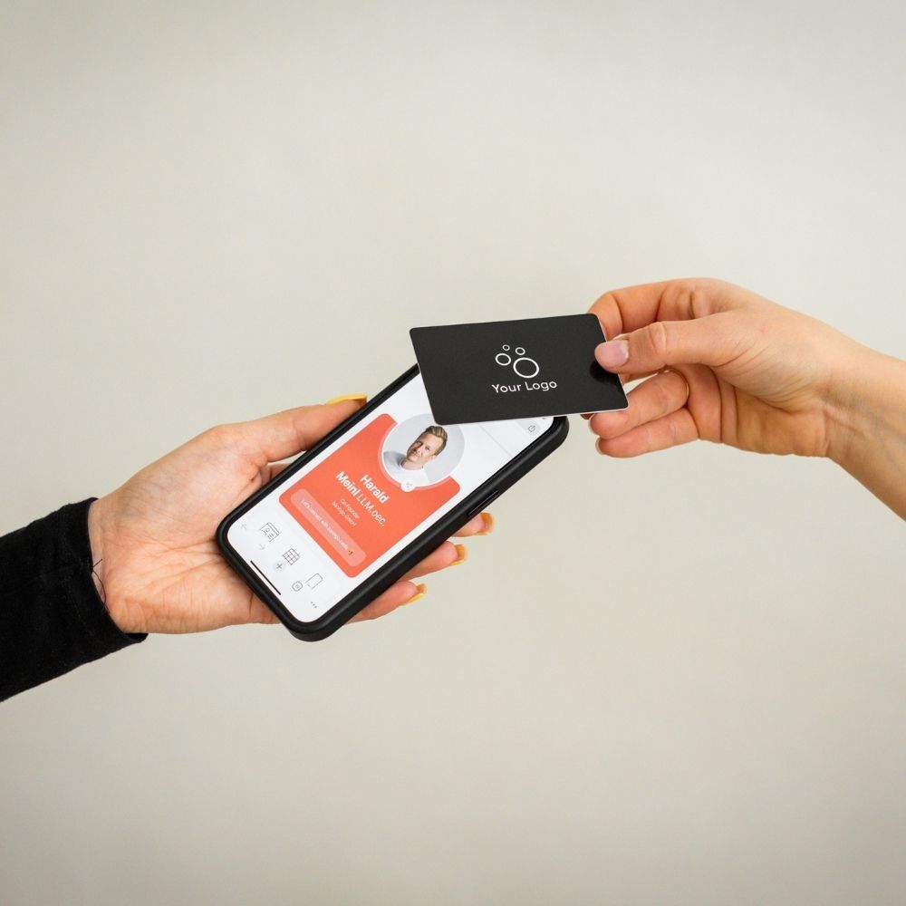 R-PVC NFC Visitenkarte Classic schwarz wird von einem Smartphone getappt, das eine geöffnete digitale Visitenkarte anzeigt