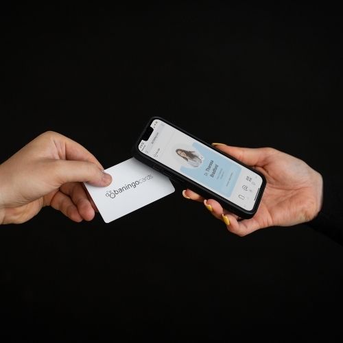 R-PVC NFC Visitenkarte Essential weiß wird von einem Smartphone getappt, das eine geöffnete digitale Visitenkarte anzeigt